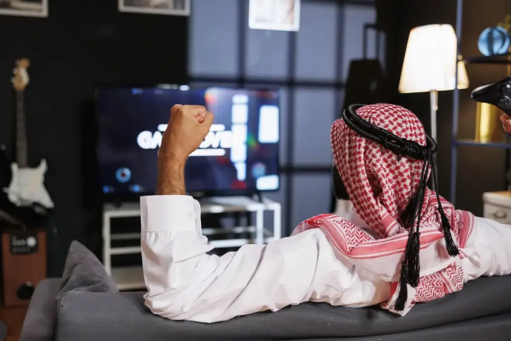 Saudi man watching IPTV Smarters Pro and celebrating while gaming – best IPTV in Dubai and UAE